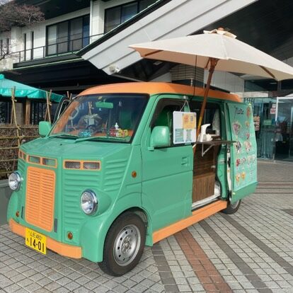 キッチンカーmanaさんのキッチンカー車体写真です。緑をベースに、オレンジのアクセントカラーが入ったバンです。